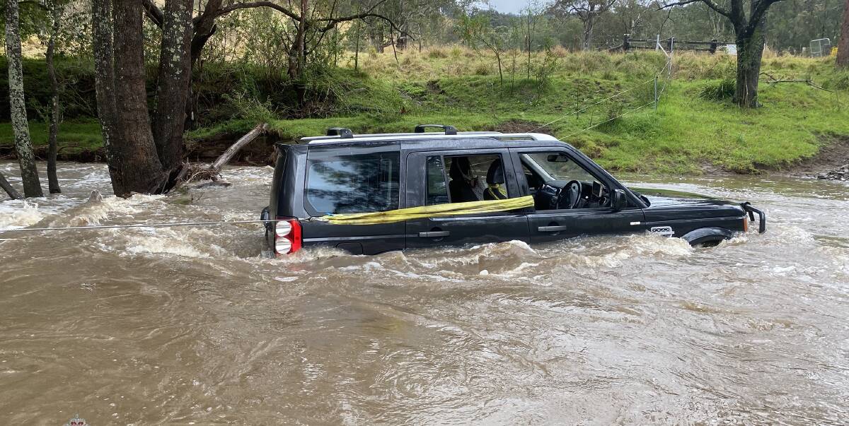 Three people have been rescued from their car by a police officer after they became trapped in floodwater near Dungog. Picture supplied.