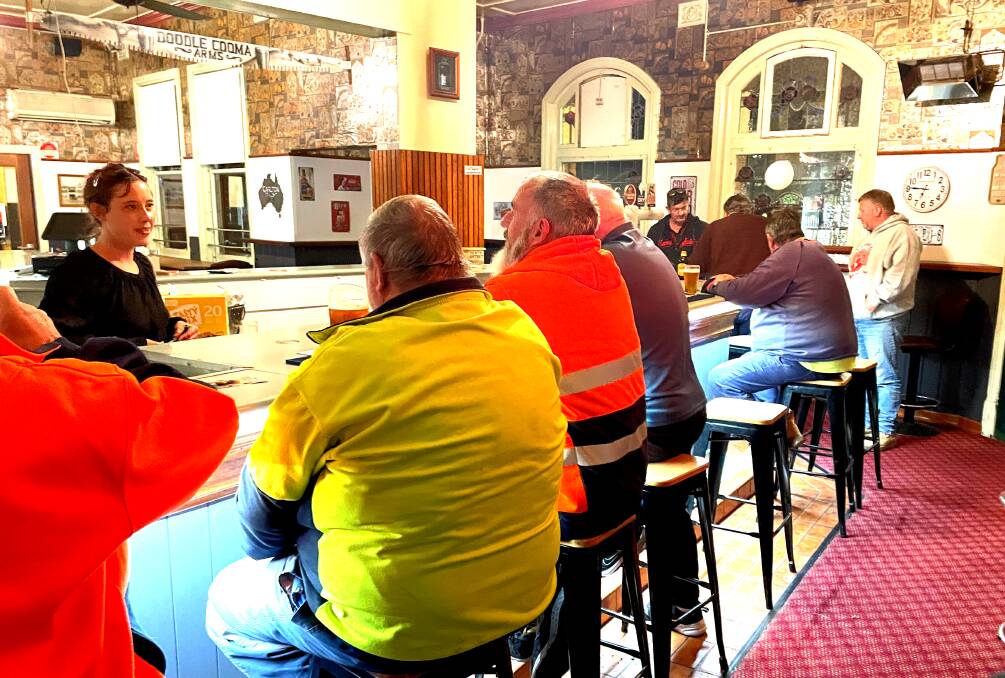 The Henty locals are back ... bar attendant Paris Broughton chats with some long-time Doodle Cooma Arms Hotel locals on Friday, June 28. Picture by Ted Howes