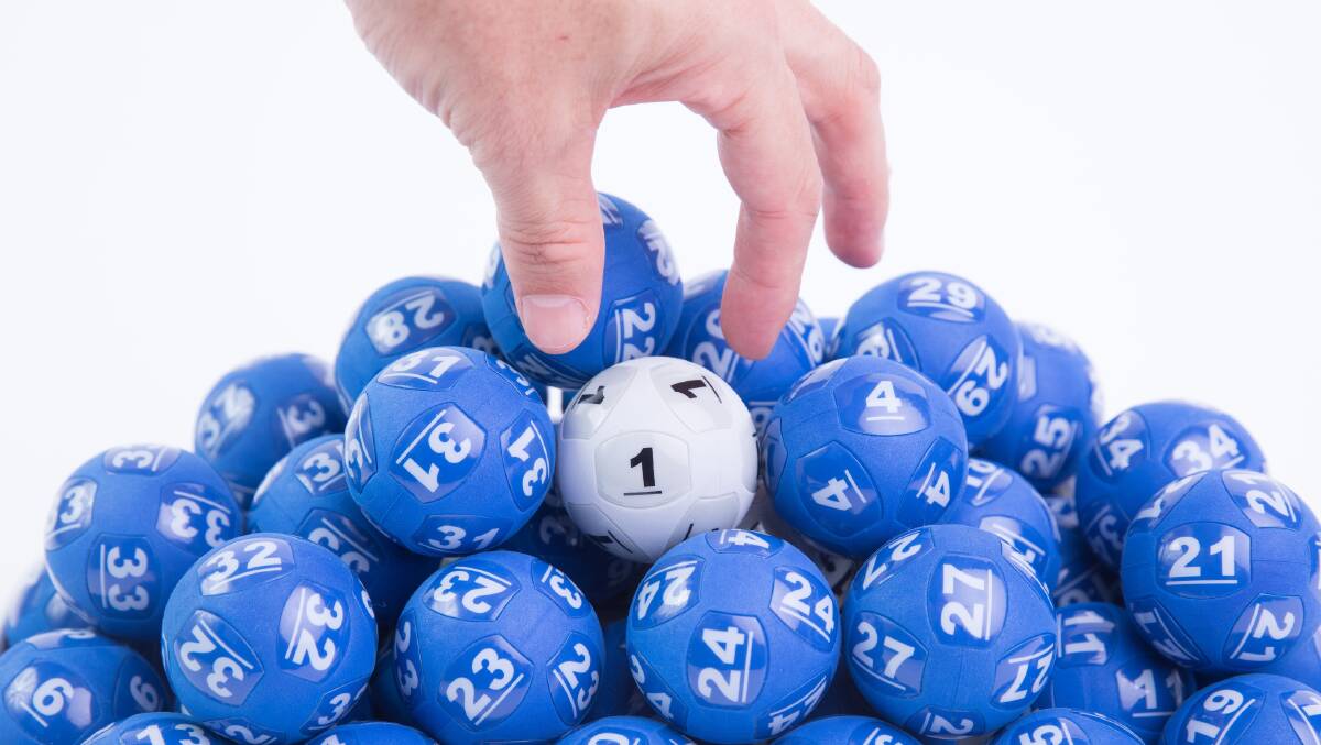 Fingers reach for a white lottery ball among a pile of blue balls. Picture supplied