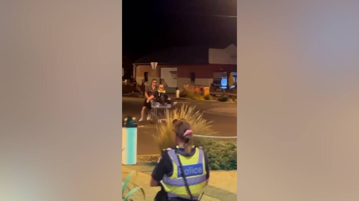 A still image from the video footage shows a police officer looking on as the joyriders circle a roundabout in a shopping trolley. File picture.