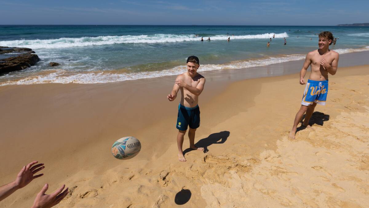 Dan Kennedy throwing a footy with his mates at Newcastle Beach. Picture Jonathan Carroll
