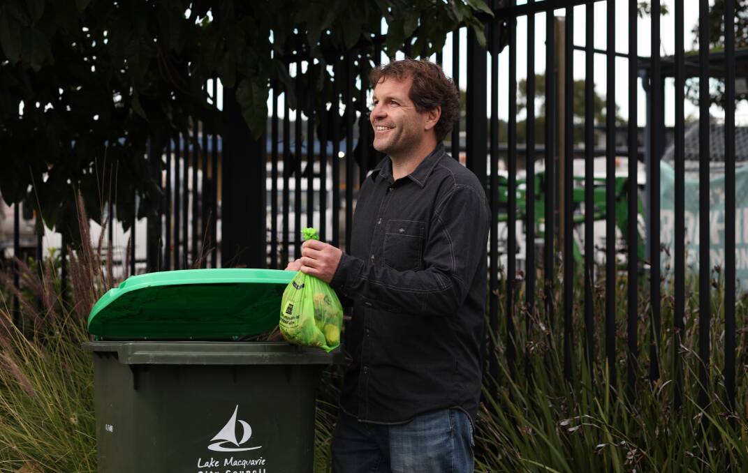 Lake Macquarie Council waste management strategy coordinator Hal Dobbins tosses a bag of organic rubbish into a council green bin. Picture by Simone De Peak