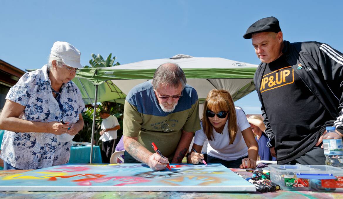 Shane Kennedy (right) overseeing a collaborative artwork with residents Shay Garside, Ian Borland & Tippy Puntasain at a community housing compound in Beresfield in 2018. Picture by Max Mason-Hubers 