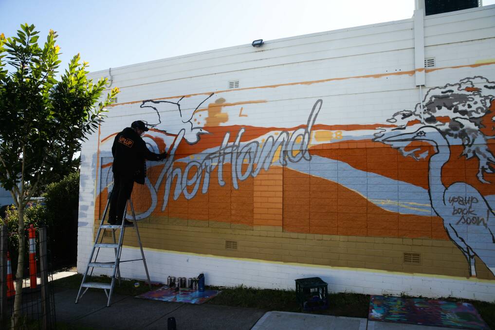 Shane Kennedy working on a mural on Sandgate Road, Shortland, in July this year. Picture by Jonathan Carroll