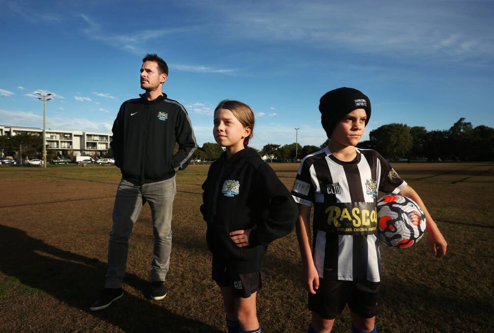 Rain Check: Brendan McManus, vice president of Cooks Hill United Football Club, with children Audrey and Austin, who play in the under-8s and under-10s. A lot of games have been rained out this season. Picture: Simone De Peak 