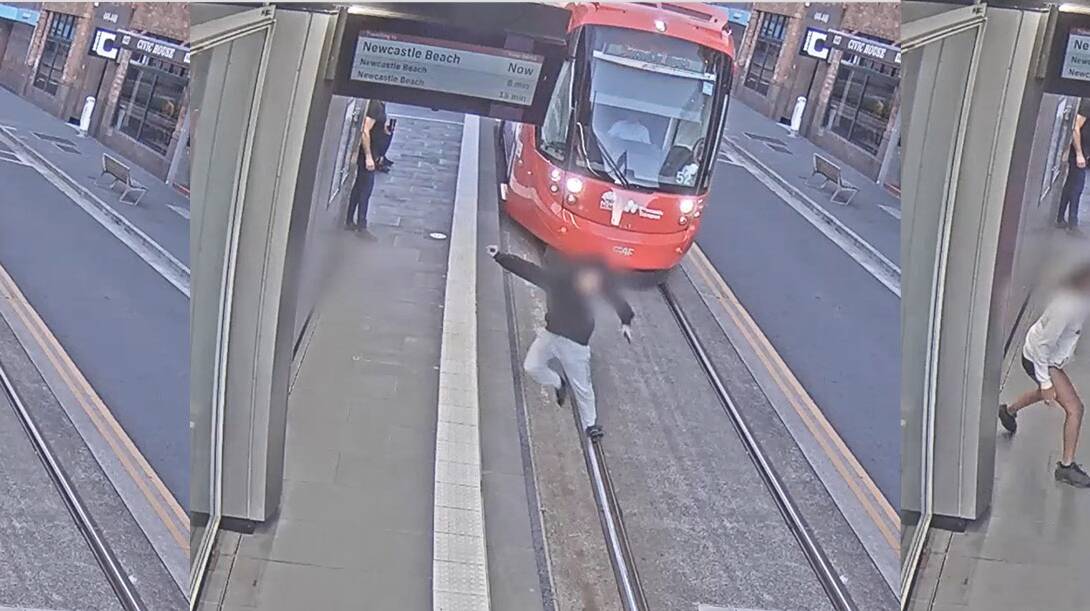 A young man leaps out of the way as a tram approaches the stop. 