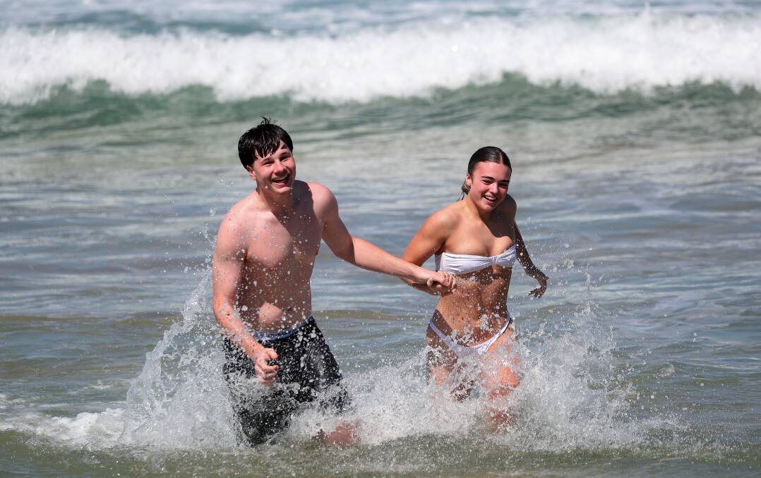 Lorcan McCullun and Charlotte Holmes soaked up the warm weather at Newcastle Beach on Wednesday. Picture by Peter Lorimer