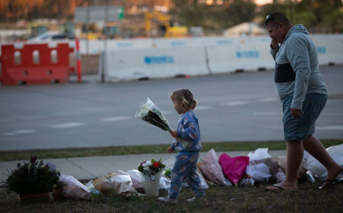 A young girl lays flowers at an impromptu memorial near the crash site. Picture by Jonathan Carroll