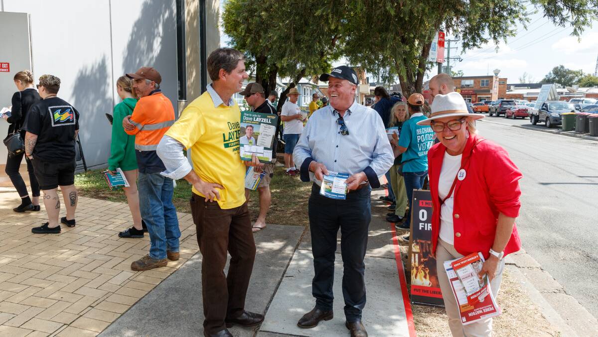 The Nationals' Dave Layzell, independent Dale McNamara and Labor's Peree Watson hand out how-to-vote cards at a busy Singleton pre-poll booth on Friday. Picture by Max Mason-Hubers 