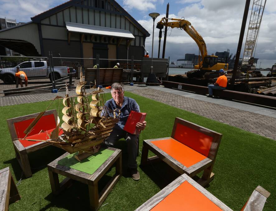 Rescued: Bob Cook with a model ship and a Lloyds Shipping Register that were salvaged from a skip bin last week. The museum's former Honeysuckle headquarters is in the background. Picture: Jonathan Carroll. 