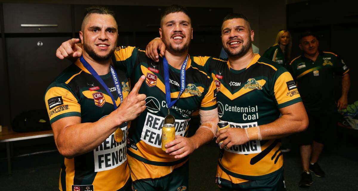 BROTHERS IN ARMS: Randall, Isaac and Scott Briggs in the dressing sheds at McDonald Jones Stadium after Macquarie's grand final triumph on Saturday afternoon. Picture: Jonathan Carroll