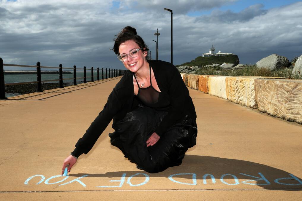 Tia Hinton, the artist behind the chalk affirmations that have been appearing on Nobbys beach, has a message that's simple and unvarnished: If you're going to be anything, be kind. Picture by Peter Lorimer.