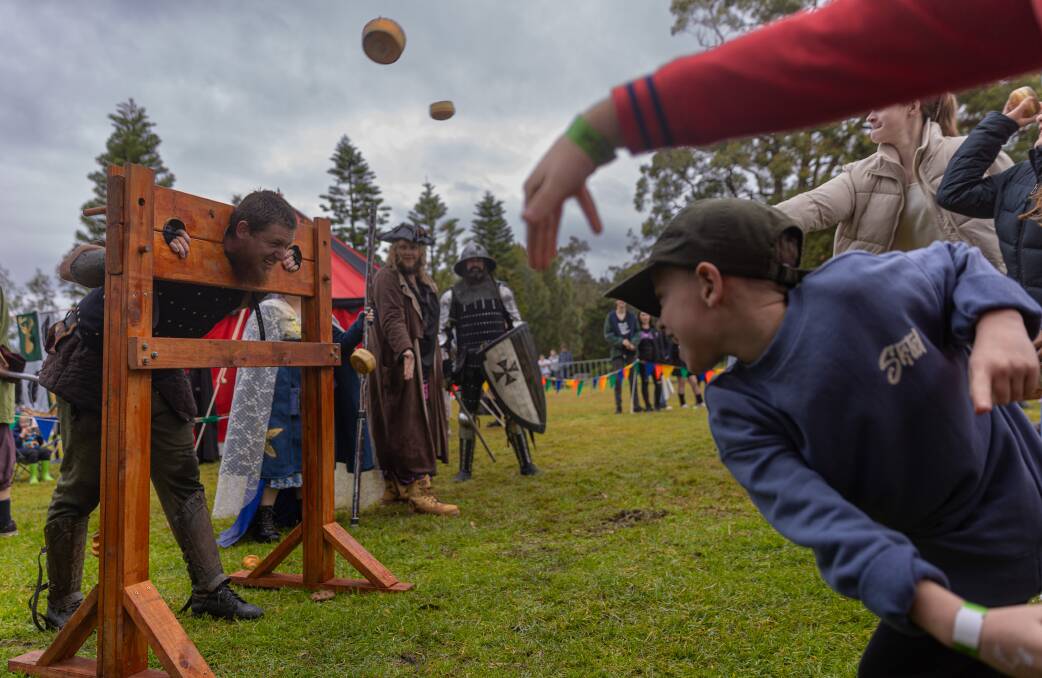 Youngsters throw bread at a LARPer bound in the pillory. Picture by Simon McCarthy