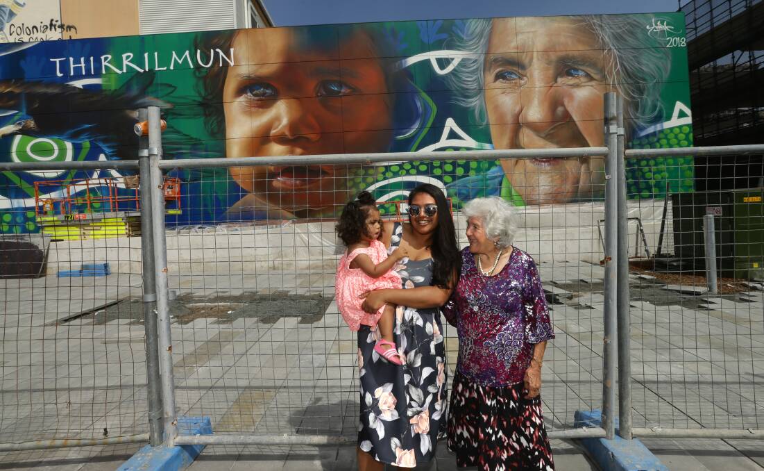 CONNECTED: Kumarah Green [centre] with her daughter Nayeli Green and grandmother Aunty June Rose, who are both depicted in Adnate's new mural on Stewart Avenue. Picture: Jonathan Carroll 
