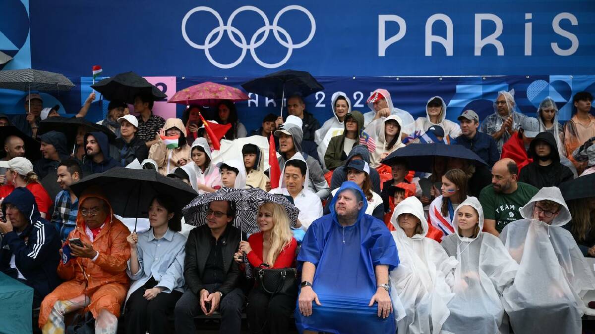 Spectators braved the weather to watch the opening ceremony from the banks of the River Seine. (Joel Carrett/AAP PHOTOS)