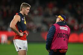 Crows' Nick Murray, who suffered a knee injury, talks to a doctor during the match with Essendon. Photo: James Ross/AAP PHOTOS