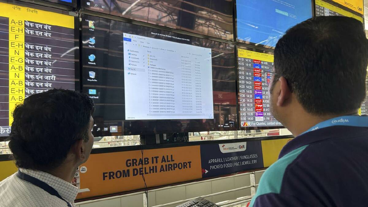 Airport officials try to reboot a flight information screen at New Delhi's international airport. (AP PHOTO)