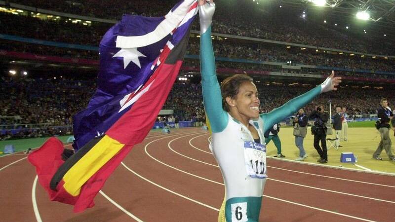 Olympic champion Cathy Freeman proudly waves both the Australian and Aboriginal flags after her historic win. Picture by Dean Lewins/AAP PHOTOS