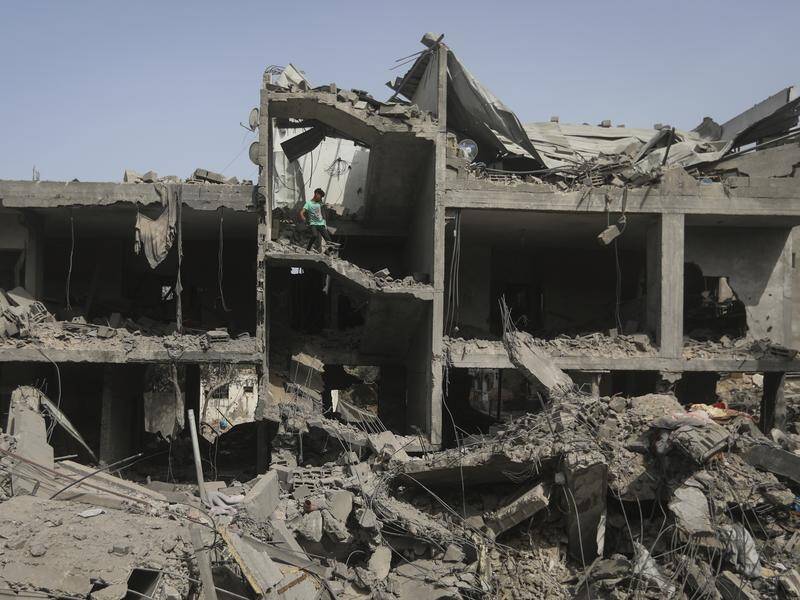 Palestinians look at the destruction after an Israeli strike on a building in Nuseirat camp, Gaza. (AP PHOTO)