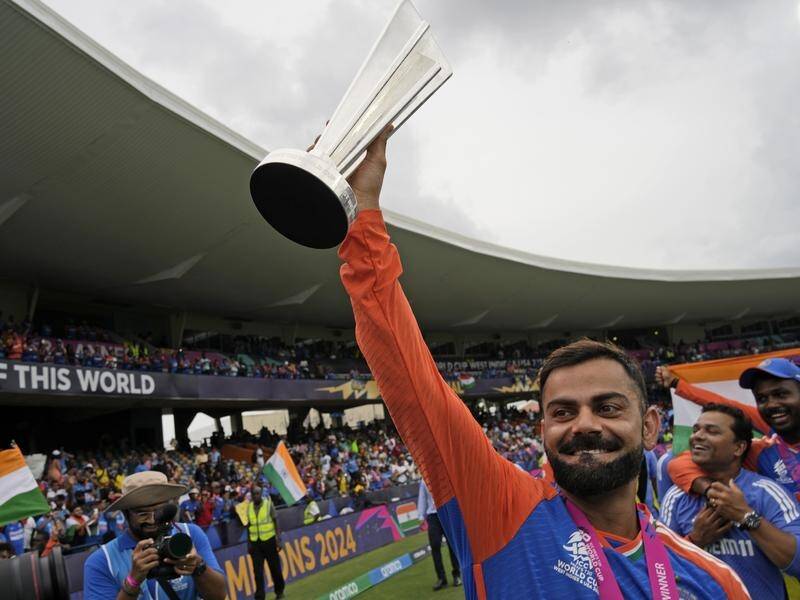 Virat Kohli hoists the World Cup aloft after announcing he'd played his last T20 international. (AP PHOTO)