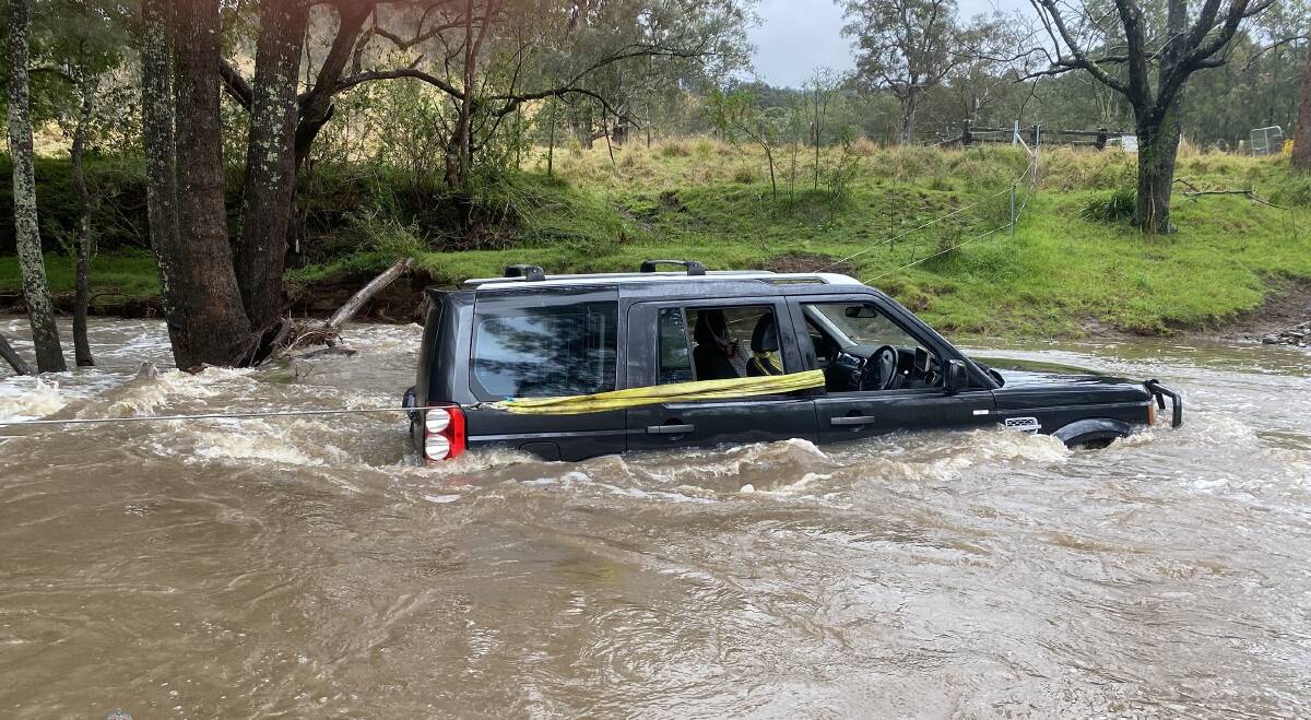 Three people were rescued from a car by Senior Constable Richard Hansen after they became trapped in floodwater near Dungog on Thursday. Picture supplied