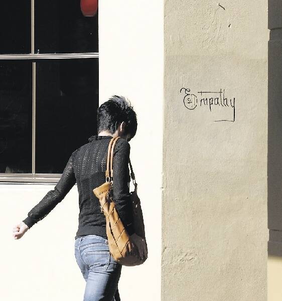 MARRED: A woman walks past the Empathy tag in Newcastle yesterday.