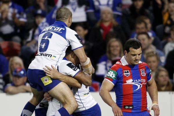 SLOW START: Knights five-eighth Jarrod Mullen, right, is not a happy man as the Bulldogs celebrate a try on Saturday night.  Picture: Jonathan Carroll