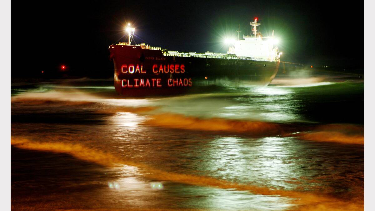 Greenpeace activists project slogans on the bow of the Pasha Bulker at Nobby s beach, They used lazer lights projecting the image from a four wheel drive.Police told them to move along at 7pm. 27th June 2007 Credit: Darren Pateman